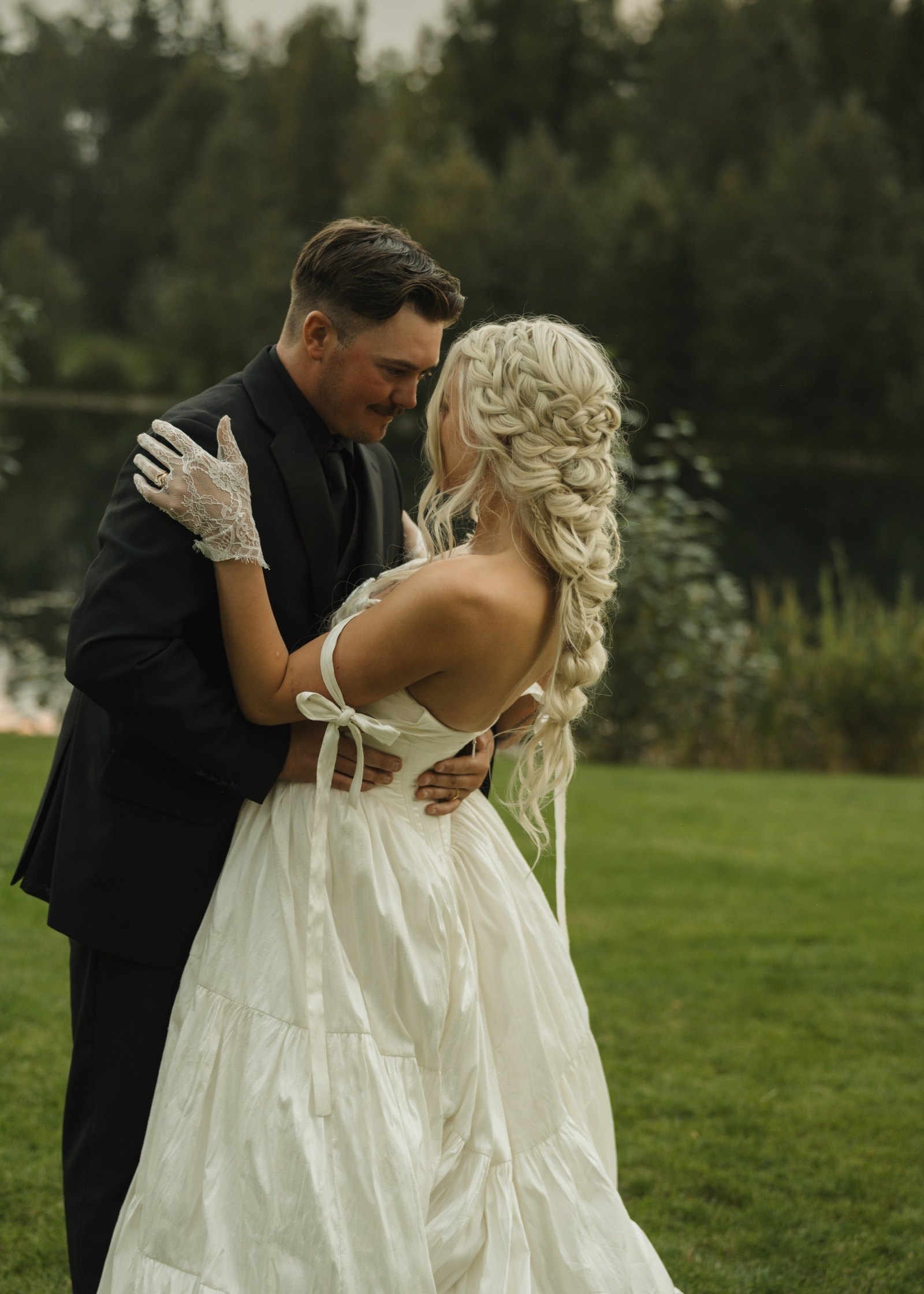 Bride with a long textured mermaid braid and face-framing pieces, outdoors with her groom